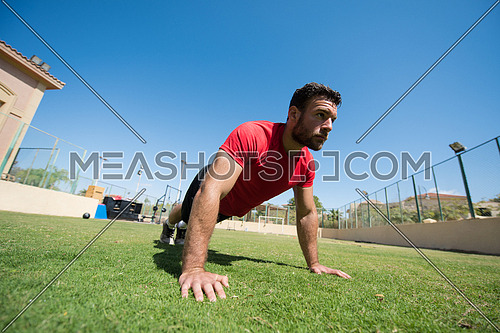 young middle eastern man athlete enjoys doing push-ups outside on a sunny day