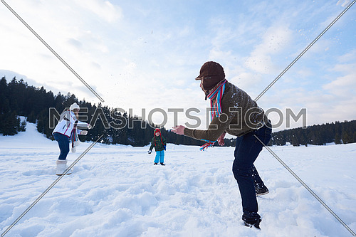 happy young  family playing in fresh snow  at beautiful sunny winter day outdoor in nature