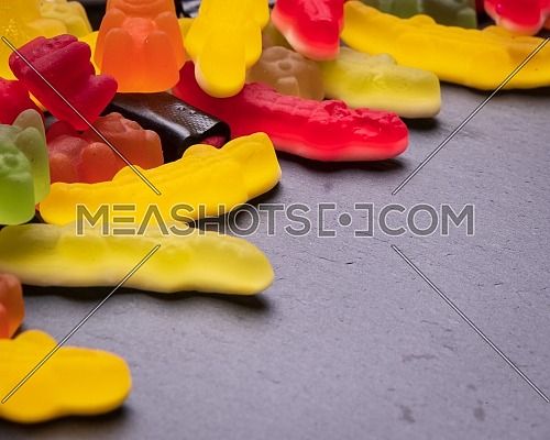Many colored candies on dark background. Top view with copy space for your greetings,square photo.