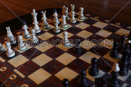 Close up black and white chess pieces on wooden board, high angle view
