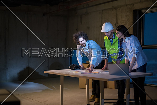 young team of business people in group, architect and engineer on construction site checking documents and business workflow using laptop computer in new startup office