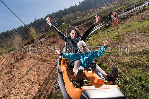 young excited mother and son enjoys driving on alpine coaster