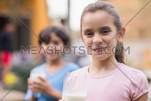 Middle Eastern girl enjoying with a glass of milk in his hand outside on summer day