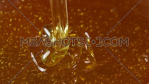 Close up dipping metal spoon in bowl of fresh thick fluid acacia honey and pouring, high angle view, slow motion