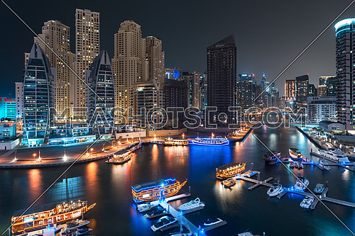 Dubai Marina Bay at night with beautiful towers and yachts reflected on water on water