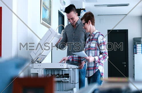 Young Beautiful Woman with assistant Making Copies Of Files In The Copy Machine