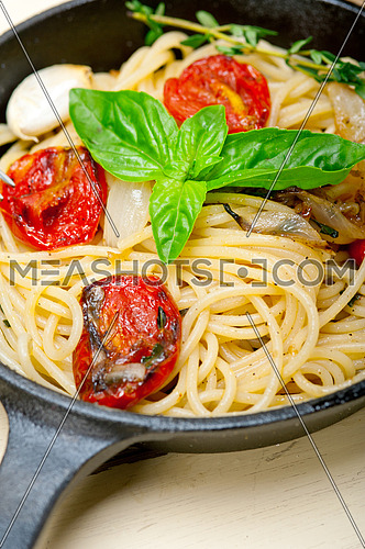 italian spaghetti pasta with baked tomatoes  basil and thyme sauce on a cast iron skillet