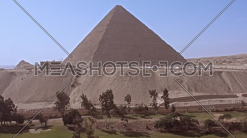 Reveal shot for The Great Pyramid of Khufu from Green field in background in Giza at day