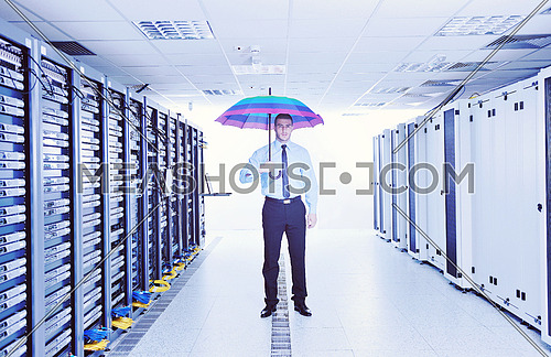 young handsome business man  engineer in 
businessman hold  rainbow colored umbrella in server datacenter room  and representing security and antivirus sofware protection concept
