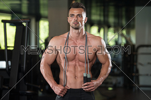 Portrait Of A Physically Fit Man Posing With Jumping Rope In Modern Fitness Center Gym
