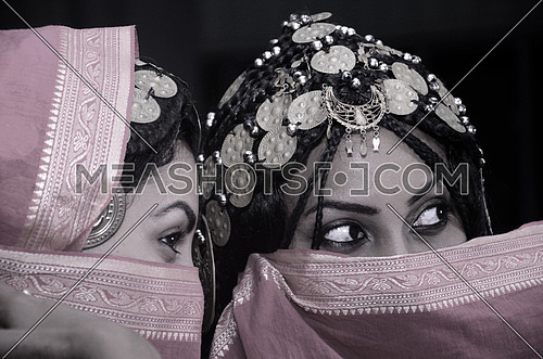 two girls wearing a traditional dress partially covering their face