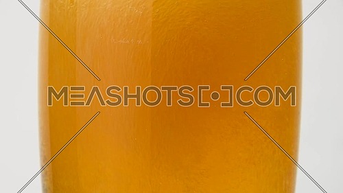 Close up background of pouring beer with bubbles and foam in glass, low angle side view, slow motion