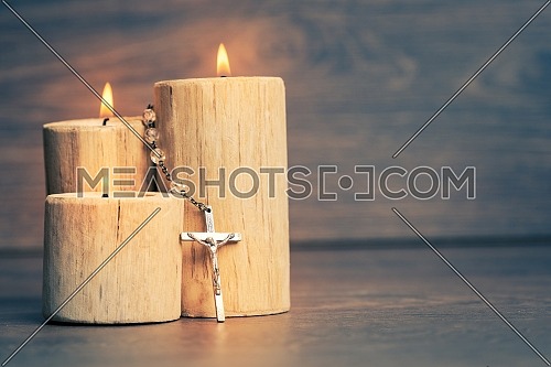 Silver rosary with Jesus on the Candle at wooden table,religion concept,vintage style with split toning.