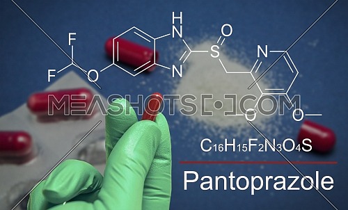 Hand with green latex glove holds a capsule of pantoprazole, chemical composition, conceptual image