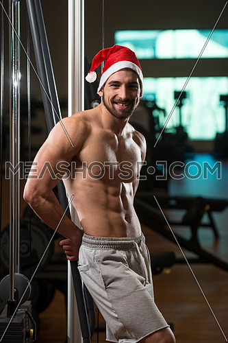 Muscular Man Wearing Santa Claus Hat In Gym