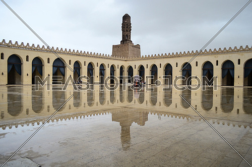 Hakim Be Amr-allah mosque on  a rainy day with a full reflection of the mosque on the marble floor.