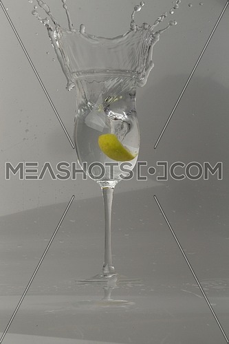 lemon slice water splash in a glass isolated on grey