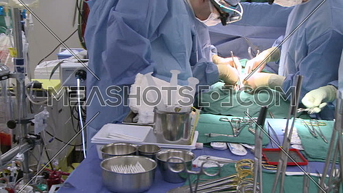 Pan Right medium shot of operating room while medical team performing surgery