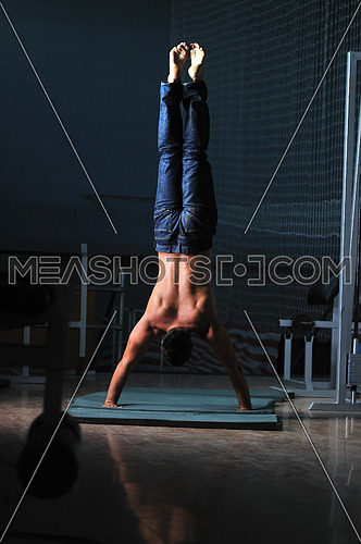 Young man performing  handstand in fitness studio. rear, back perspective.