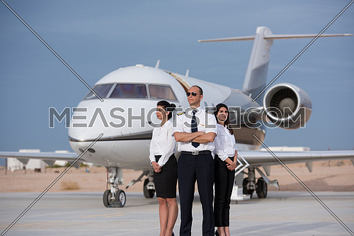 portrait of a successful middle eastern pilot with young beautiful stewardess at the airport in front of the private airplane