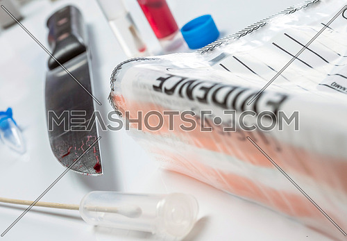 knife Spotted with blood along with a evidence bag in scientific laboratory, conceptual image