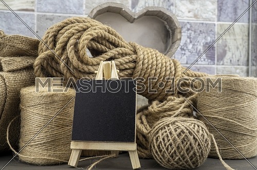 Assorted balls of hemp twine and string with skeins of rope and slate chalkboard in a close up rustic still life
