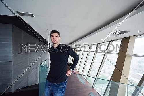 portrait of young successful startup business man in penthouse,  modern bright duplex office apartment interior  with staircase and big windows