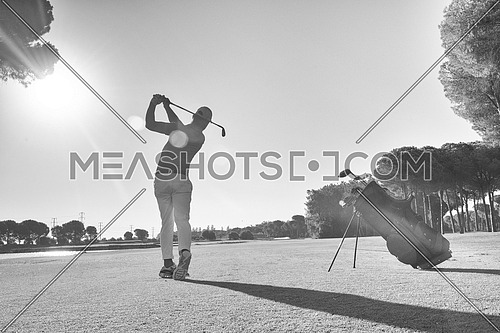 golf player hitting shot with club on course at beautiful morning black and white