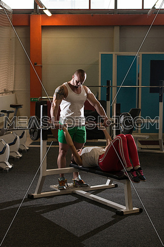 Personal Trainer Showing Young Woman How To Train Bench Chest In The Gym