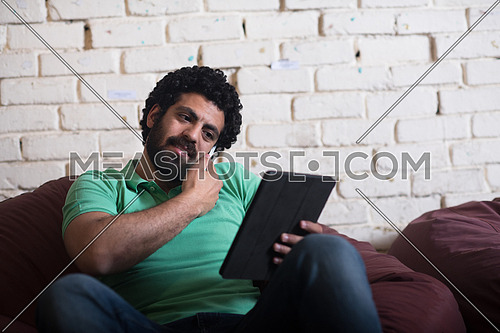 casual middle eastern young businessman talking on the phone, and tablet used in modern stylish office