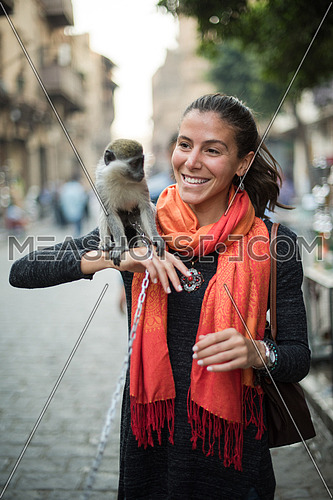 portrait of a young beautiful middle eastern woman who enjoys in the city with a monkey on her shoulder