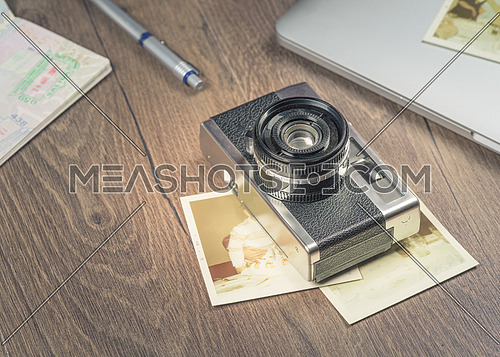 Vintage image with old Camera,old photo,laptop,pen and passport on wood table.