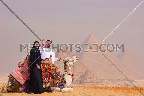 portrait of  Emiratie man and his wife as tourists at the pyramids