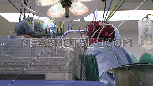 Low angel shot for medical team performing surgery and surgical tray in foreground