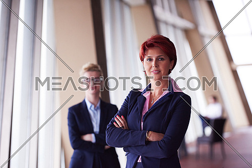 portrait  of two corporate business woman at modern bright office interior standing in group as team