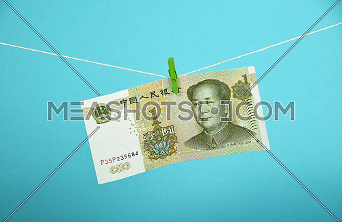 China economy growth, strengthening of Chinese yuan illustrated, one yuan banknote hanged ascending with pin at rope over blue background