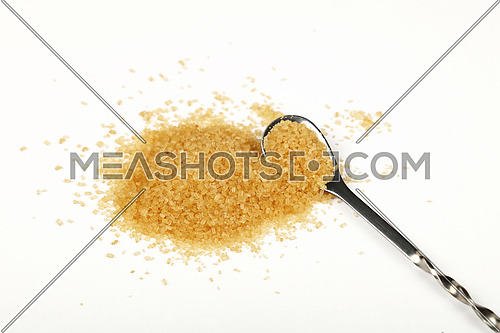 Metal spoon full of brown cane sugar with pinch of sugar spilled around isolated on white background, close up, high angle view