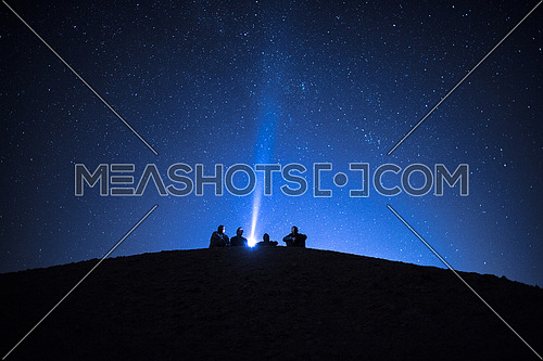 Group of friends stargazing in the desert at Night