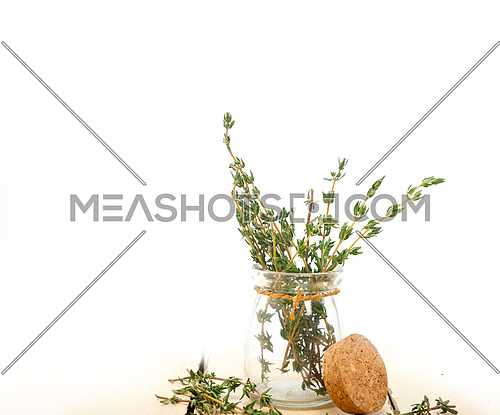 fresh thyme on a glass jar over a white wood rustic table