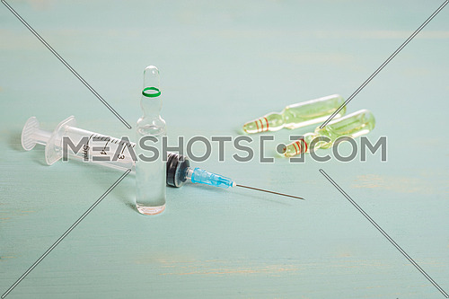 Medical vials and syringe isolated on green background, vaccination concept and disease treatments