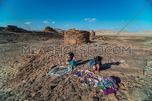 mid Shot for a little girl sits beside stone house Called Nawamis area from Sinai Trail at day.