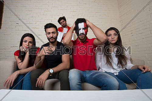 A group of middle eastern  friends watching a football game in the living room
