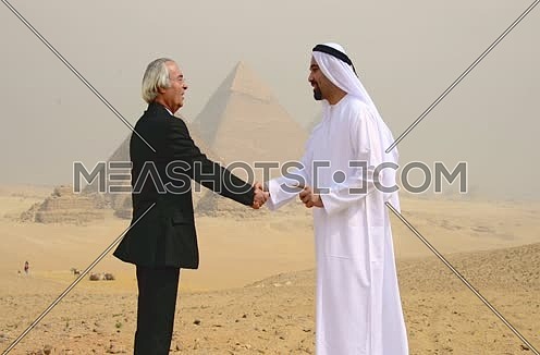 successful emiratie and egyptian business men at pyramids shaking hands