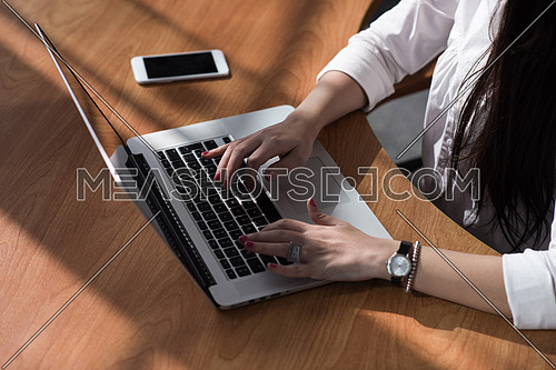 Close up of a young female executive hands typing on a computer in a modern office