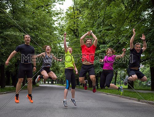 group of healthy runners team jumping in the air at city park during  morning training