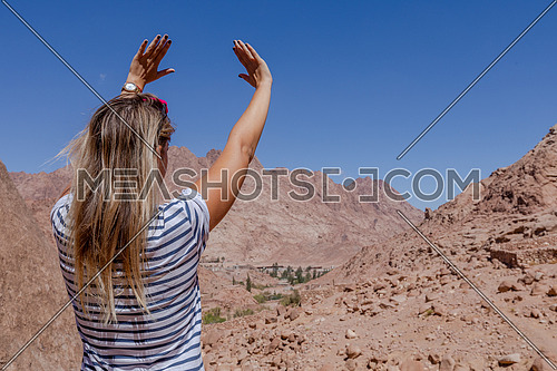 Long shot for a female tourist from behind exploring Sinai Mountain for wadi Freij by day.