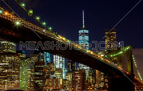 Brooklyn Bridge closeup over East River at night in New York City Manhattan with lights and reflections.