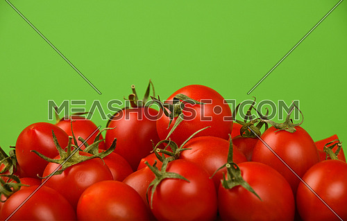 Red ripe fresh small cherry tomatoes over green background close up