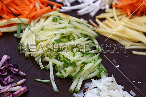 Close up assorted cut and sliced fresh vegetables on black cooking board, high angle view