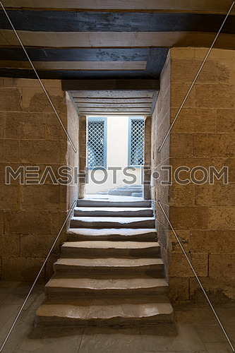 Aged narrow dark vaulted passage and staircase leading to outdoor small lobby with two yellow wooden windows, Mosque of Soliman Agha, Cairo, Egypt